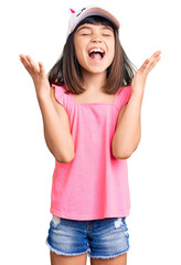 Young little girl with bang wearing funny kitty cap celebrating mad and crazy for success with arms...