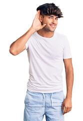 Fototapeta premium Young hispanic man wearing casual clothes smiling with hand over ear listening an hearing to rumor or gossip. deafness concept.