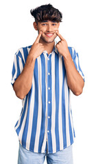 Young hispanic man wearing casual clothes smiling with open mouth, fingers pointing and forcing cheerful smile