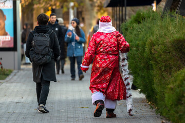 A young man dressed as Santa Claus walking on a city street