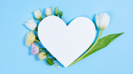 Natural white and blue-violet flowers near the white paper heart.