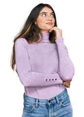 Young beautiful teen girl wearing turtleneck sweater with hand on chin thinking about question, pensive expression. smiling and thoughtful face. doubt concept.