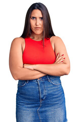 Young beautiful brunette woman wearing casual sleevelss t-shirt skeptic and nervous, disapproving expression on face with crossed arms. negative person.