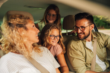 Portrait of parents and daughters enjoying road trip and traveling by car