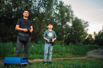 Father and son holding remote controllers having fun in nature.