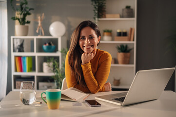 Portrait of a smiling young woman looking into the camera while working at home