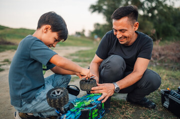 Dad and son enjoying time together fixing toy car wheel outdoors.