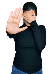 Young hispanic woman wearing casual clothes covering eyes with hands and doing stop gesture with...
