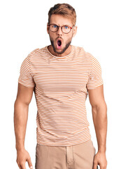 Young caucasian man wearing casual clothes and glasses afraid and shocked with surprise and amazed expression, fear and excited face.