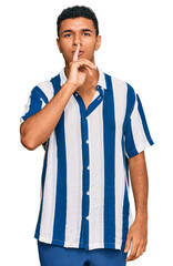 Young arab man wearing casual clothes asking to be quiet with finger on lips. silence and secret concept.