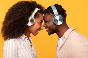 Happy black couple sharing headphones, enjoying music together