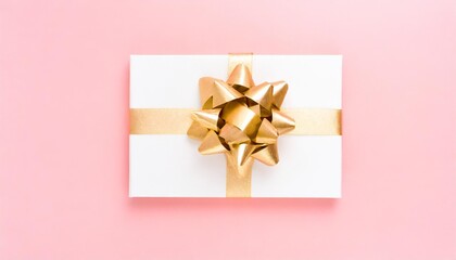 blank gift card with golden bow on pink background top view space for text