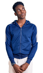 Young african american man wearing sportswear smiling looking to the side and staring away thinking.