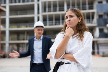 Fototapeta premium Portrait of a frustrated young woman who had a misunderstanding with a man contractor about cooperation