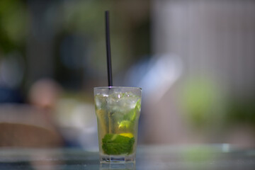 Refreshing green lemonade in a glass on the table against the background of nature. Freshly squeezed drinks with ice. Lemonade with lemon, mint lime and herbs