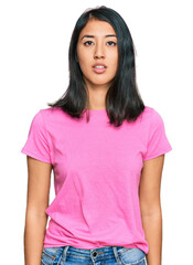 Beautiful asian young woman wearing casual pink t shirt relaxed with serious expression on face. simple and natural looking at the camera.