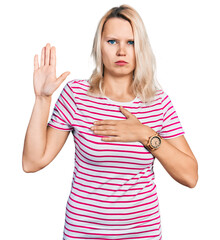 Young caucasian woman wearing casual clothes swearing with hand on chest and open palm, making a...