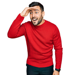 Fototapeta premium Young hispanic man wearing casual clothes very happy and smiling looking far away with hand over head. searching concept.