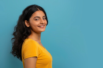 Profile portrait of attractive young indian woman posing on blue