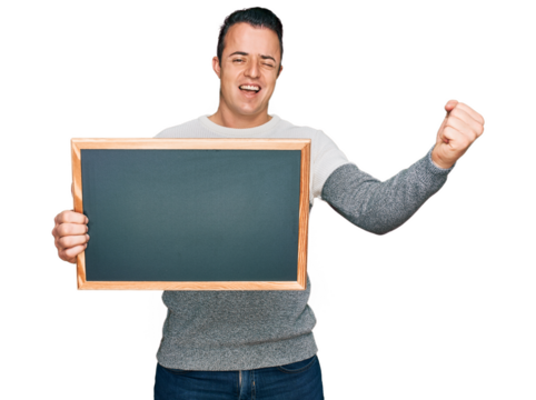 Handsome young man holding blackboard screaming proud, celebrating victory and success very excited with raised arms