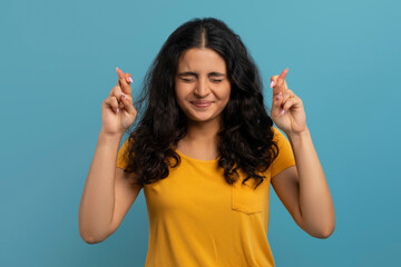 Excited young indian lady with closed eyes and crossed fingers
