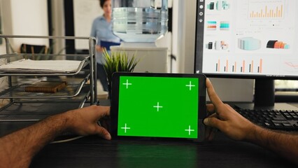 Fototapeta na wymiar POV of manager uses tablet with greenscreen template, looking at chromakey layout and sitting in coworking space. Young man examining blank mockup copyspace on device display.