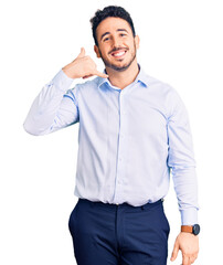 Young hispanic man wearing business clothes smiling doing phone gesture with hand and fingers like talking on the telephone. communicating concepts.