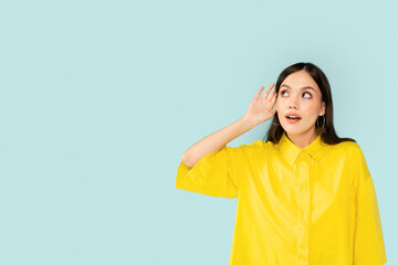 Curious young brunette woman eavesdrop on blue background