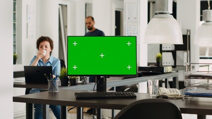 Monitor with greenscreen on empty desk in modern coworking space, pc showing isolated mockup template with copyspace. Device with chromakey display used for small business operations. Tripod shot.