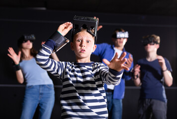 Portrait of excited surprised preteen boy with vr headset goggles on head playing virtual reality...