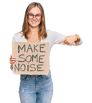 Beautiful blonde woman holding make some noise banner smiling happy pointing with hand and finger