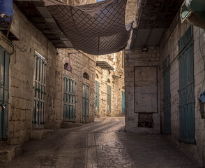 The narrow dark alley with stone wall houses in the old town of Bethlehem at Palestinian...