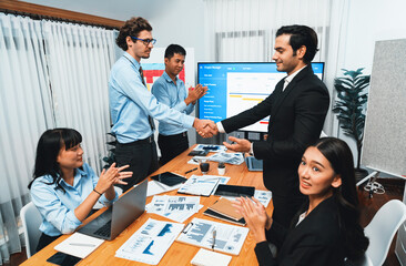 Cheerful meeting room, businesspeople celebrate with handshaking. Successful project was completed...