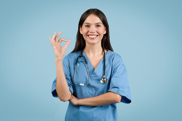 Confident nurse in blue gives OK sign, signifying approval or success.