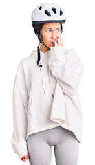Beautiful brunette young woman wearing bike helmet and sporty clothes looking stressed and nervous with hands on mouth biting nails. anxiety problem.