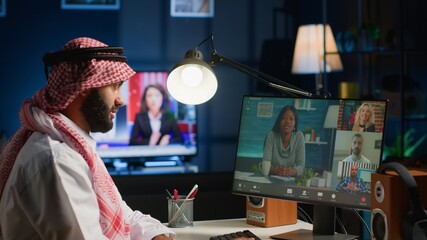 Arabic team leader holding online video conference meeting with remotely working subalterns. Teleworking business executive sitting at desk in cozy apartment, discussing with workers during video call