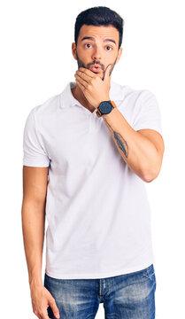 Young handsome hispanic man wearing casual clothes looking fascinated with disbelief, surprise and amazed expression with hands on chin