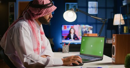 Muslim man scrolling on isolated screen laptop, checking social media posts. Self employed person...