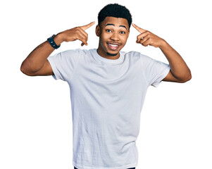 Young african american man wearing casual white t shirt smiling pointing to head with both hands finger, great idea or thought, good memory