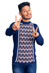Handsome latin american young man wearing casual winter sweater smiling looking to the camera...