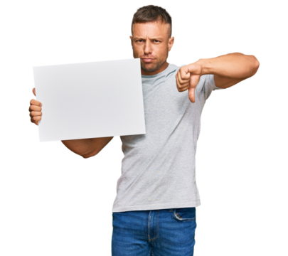 Handsome muscle man holding blank empty banner with angry face, negative sign showing dislike with thumbs down, rejection concept
