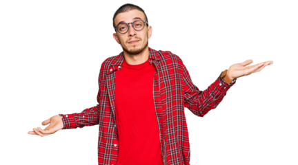 Hispanic young man wearing casual clothes clueless and confused expression with arms and hands raised. doubt concept.