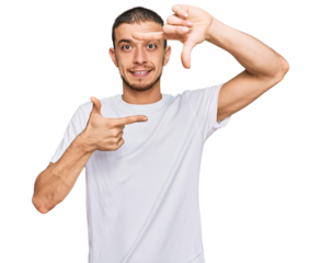 Hispanic young man wearing casual white t shirt smiling making frame with hands and fingers with happy face. creativity and photography concept.