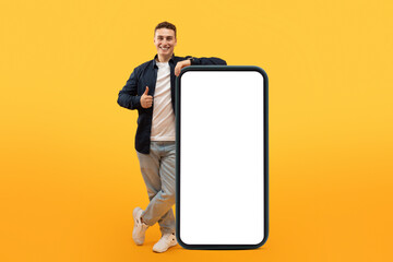Excited guy stand by big smartphone with white blank screen