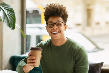 Portrait of happy young black guy enjoying coffee