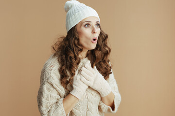 surprised modern woman in beige sweater, mittens and hat