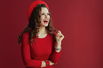 smiling elegant woman in red dress and beret on red background