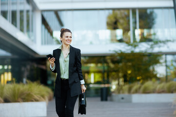 happy woman worker near business center using phone and walking