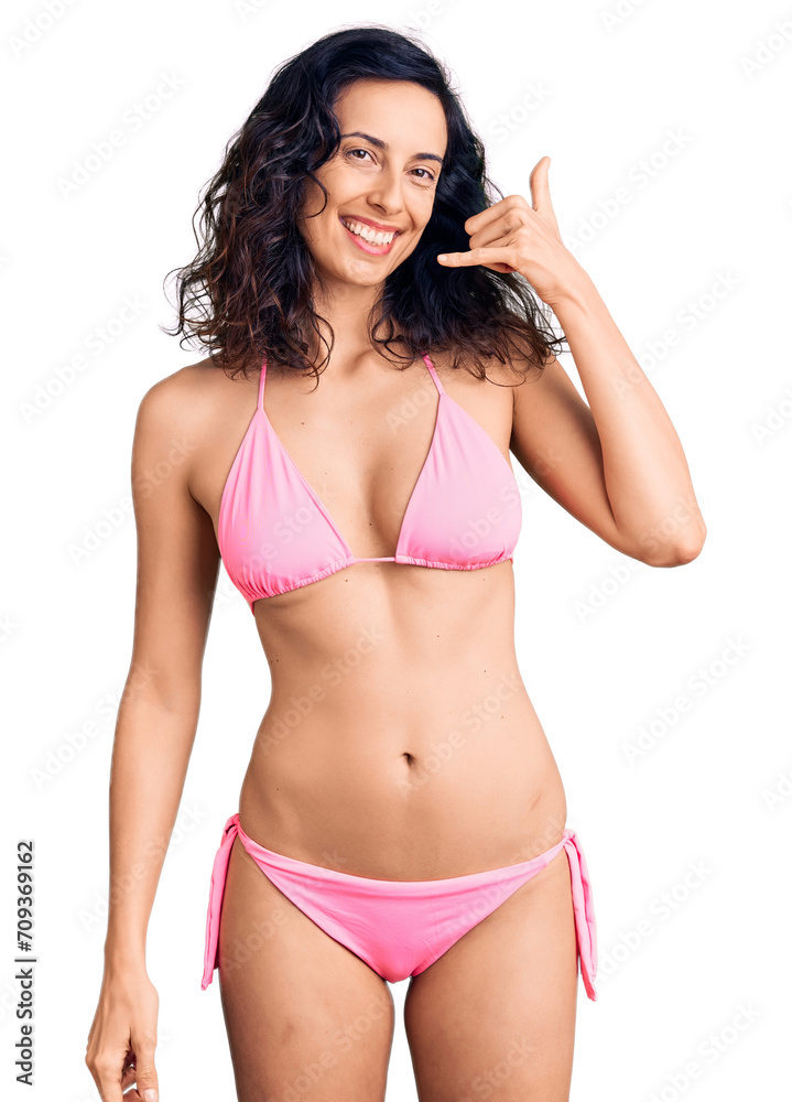 Wall mural young beautiful hispanic woman wearing bikini smiling doing phone gesture with hand and fingers like