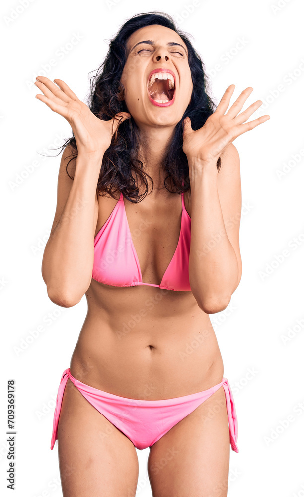 Wall mural young beautiful hispanic woman wearing bikini celebrating mad and crazy for success with arms raised